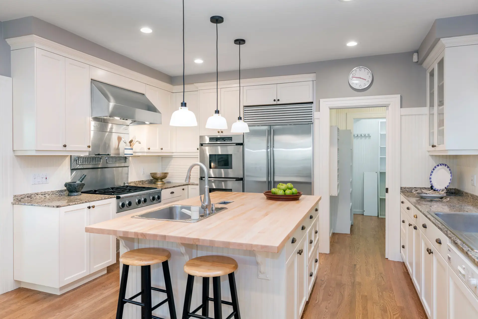 Luxury kitchen renovation in Vancouver featuring white custom cabinets, island, and hardwood floors