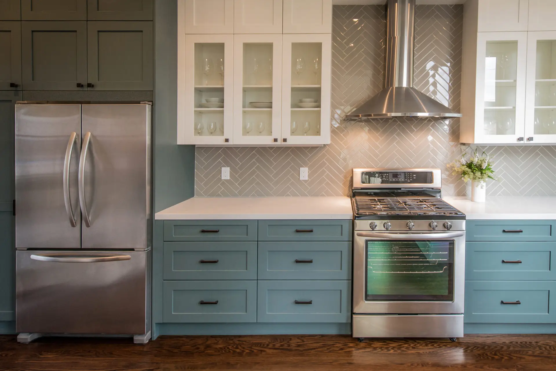 Modern kitchen renovation in Vancouver featuring teal base cabinets, white upper cabinetry, and stainless steel appliances