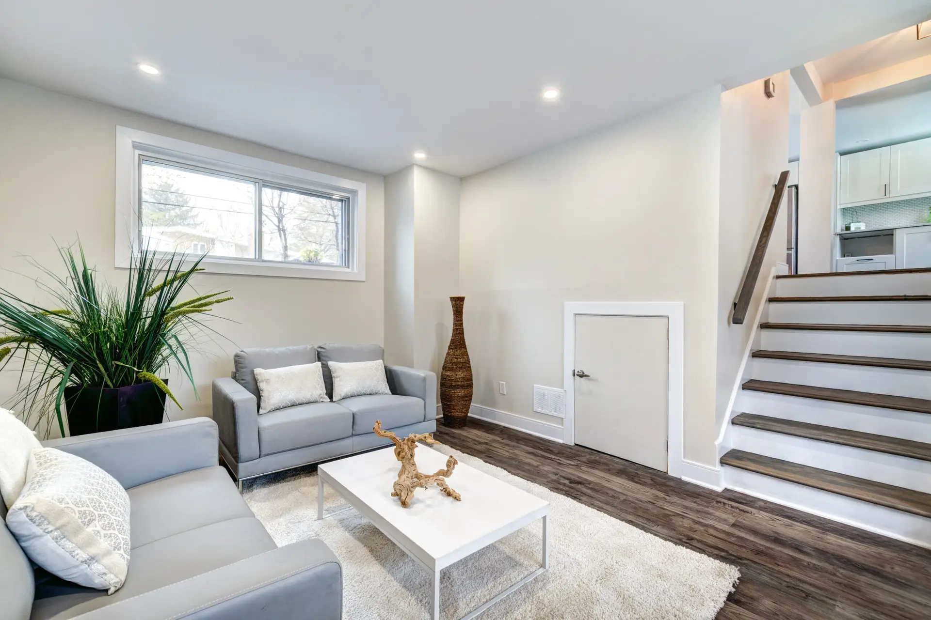 Modern basement renovation in Vancouver featuring custom white shelving and bright laundry room storage.
