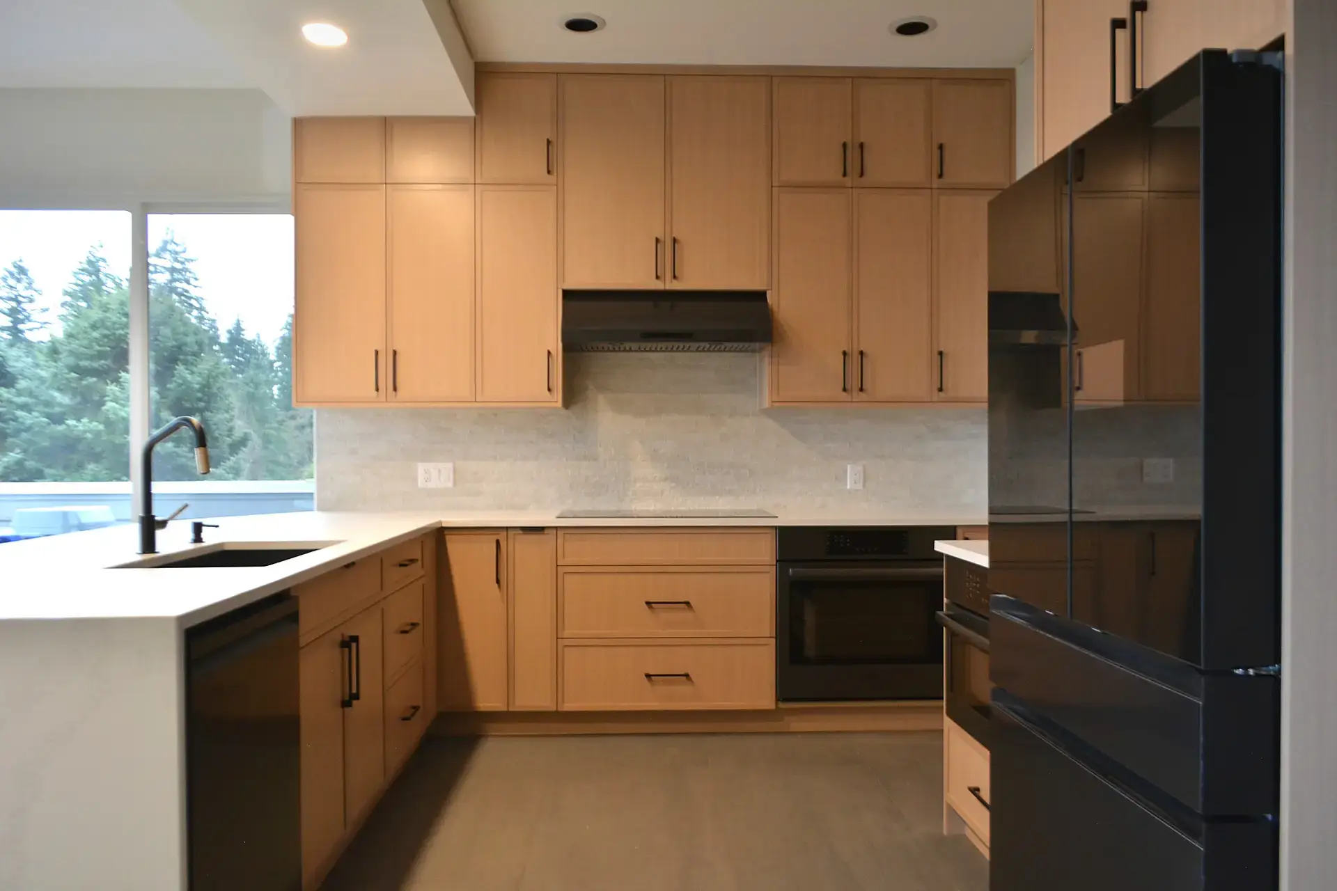 Modern kitchen renovation in Vancouver featuring light wood cabinetry and white tile backsplash